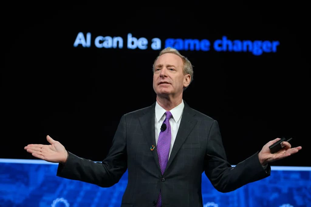 “AI can be a game changer” гэсэн бичигтэй дэлгэцийн өмнө үг хэлж буй Microsoft-ийн ерөнхийлөгч Брэд Смит