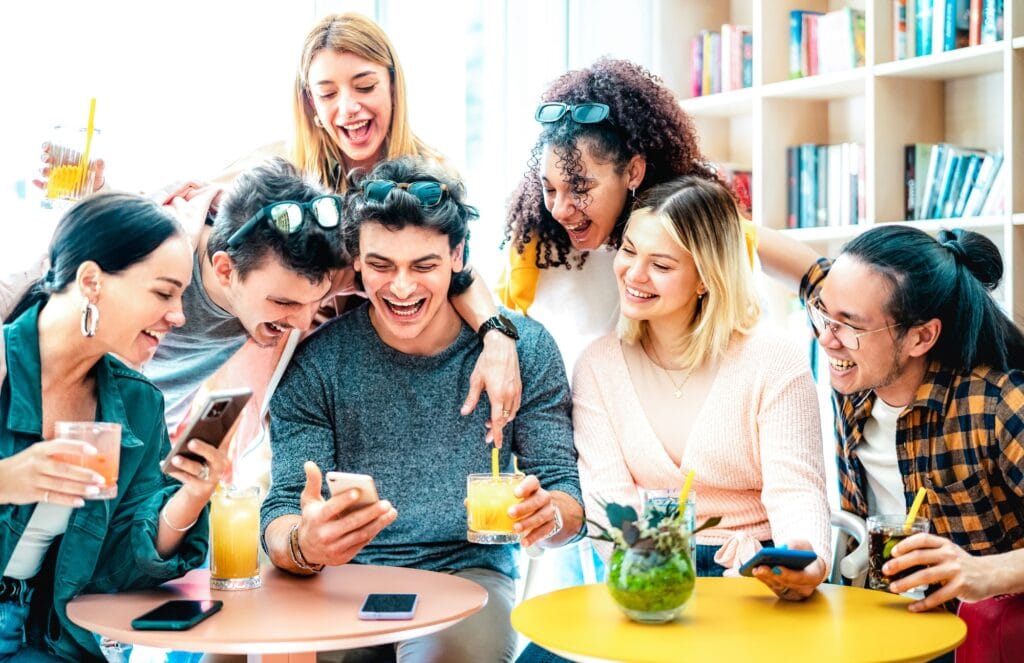 Trendy friends watching viral video on mobile phone at cocktail bar